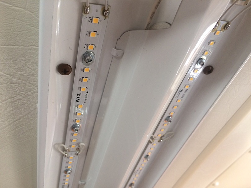 Fixture with cover off. Dark screws visible.  They wind up on one side but the other side had to have new holes.